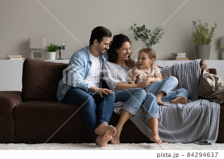 Happy parents with daughter relaxing on comfortable couch at home Happy parents with daughter relaxing on comfortable couch at home 84294637