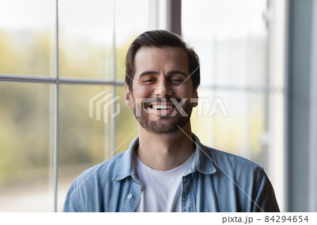 Headshot portrait of laughing young casual male standing indoors 84294654