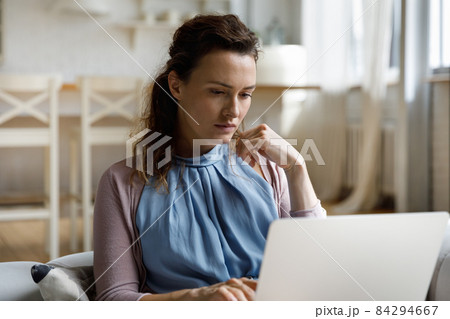 Thoughtful young woman looking at computer screen. Thoughtful young woman looking at computer screen. 84294667