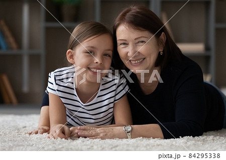 Head shot portrait of smiling mature grandmother and little granddaughter Head shot portrait of smiling mature grandmother and little granddaughter 84295338