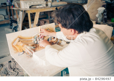 restorer working with antique decor element 84296497