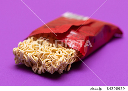 Opened Package with Uncooked Instant Noodles on Violet Background Opened Package with Uncooked Instant Noodles on Violet Background 84296929