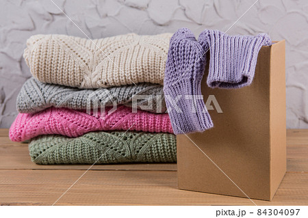 stack of folded sweaters on the table, one sweater in a box, internet commerce concept 84304097