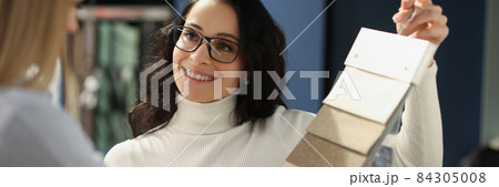 Smiling sales assistant shows samples with fabrics 84305008