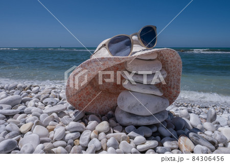 Hat and sunglasses on stone beach of Mediterranean Sea in Marina di Pisa Italy 84306456