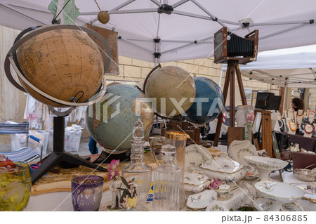 Old globes and porcelain on stand of antiques market in Arezzo Italy 84306885