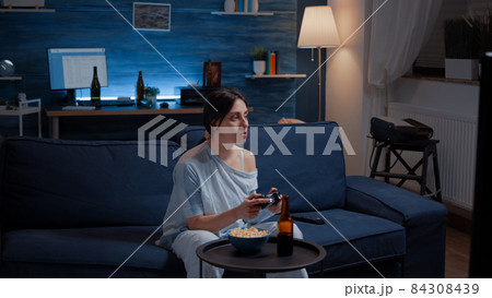 Focused determined woman playing video game late night 84308439