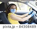 Young woman in a mask sitting in a car 84308489