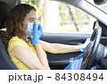 Young woman in a mask sitting in a car 84308494