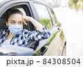 Young woman in a mask sitting in a car 84308504