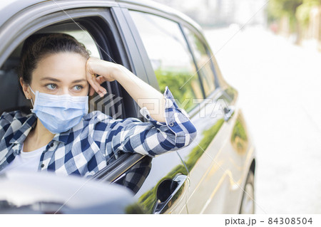 Young woman in a mask sitting in a car 84308504