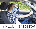 Young woman in a mask sitting in a car 84308506