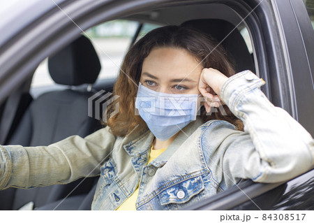 Young woman in a mask sitting in a car Young woman in a mask sitting in a car 84308517