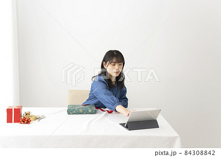 テーブルでリボンのかけ方をネットで検索してみながら結ぶ女性 84308842
