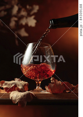 Brandy is poured from a bottle into a glass. 84309188