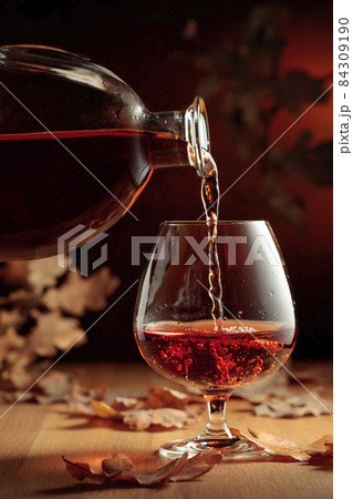 Cognac is poured into a glass from a bottle. 84309190