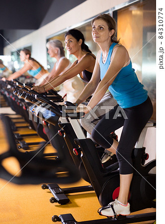 Woman riding stationary bike at fitness center Woman riding stationary bike at fitness center 84310774