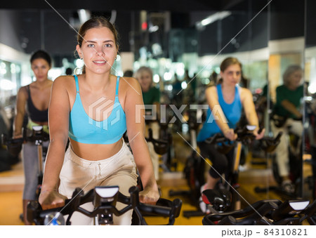 Woman taking indoor cycling class at gym 84310821