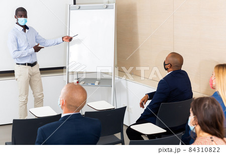 african male instructor explained something to students in meeting room during epidemic 84310822