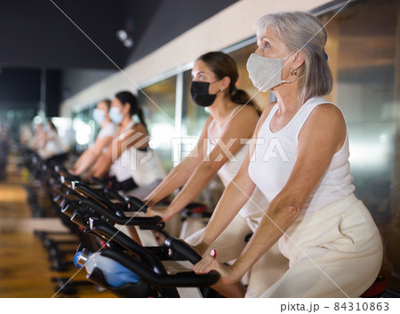 Mature woman in mask taking cycling class 84310863
