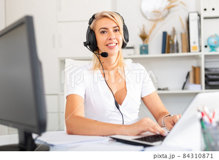 Female operator talking with customer using headset at company office Female operator talking with customer using headset at company office 84310871