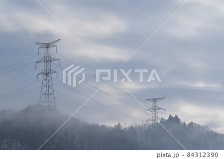 雲の下で霧がかかっている中に送電塔が立っている風景の写真素材 ...