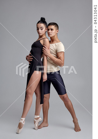 Two athletic modern ballet dancers are posing against a gray studio background. 84313041