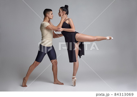 Two athletic modern ballet dancers are posing against a gray studio background. 84313069