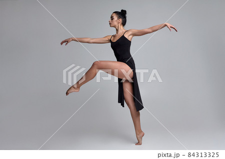 Dancing ballerina in a black dress. Contemporary graceful performance on a gray background. Dancing ballerina in a black dress. Contemporary graceful performance on a gray background. 84313325