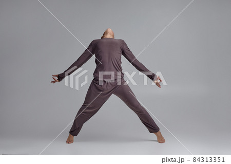 Photo of an athletic man ballet dancer dressed in a gray tracksuit, making a dance element against a gray background in studio. Photo of an athletic man ballet dancer dressed in a gray tracksuit, making a dance element against a gray background in studio. 84313351