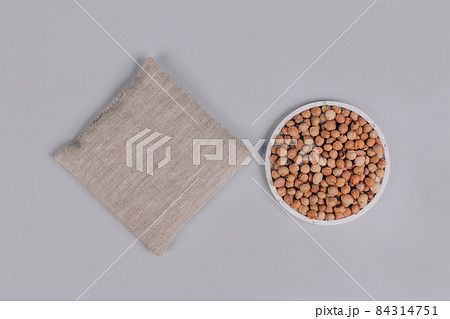 Top view on cherry stone pillow, cherry pit filled pillow with cherry stones around on gray background. Natural heat or cool pack. Alternative medicine and therapy, pit sack for spa massage. Mockup 84314751