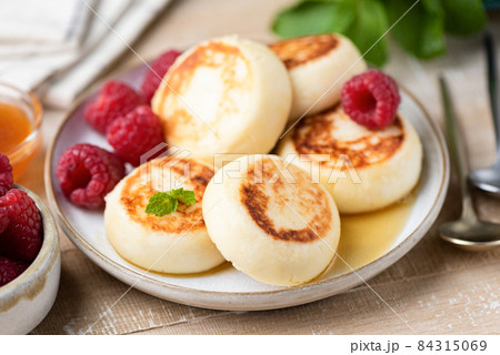Cheese fritters Syrniki with raspberries and honey Cheese fritters Syrniki with raspberries and honey 84315069