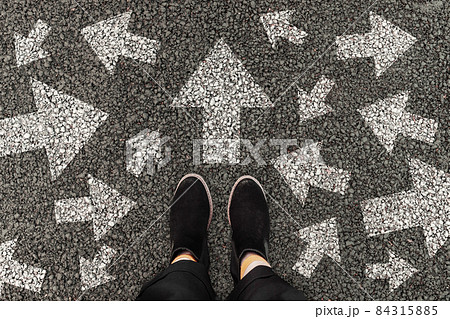 Person standing on road with arrow markings pointing in different directions, decision making concept 84315885