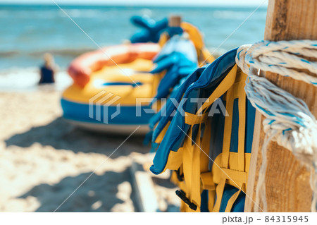 Many colorful yellow blue marine life vest signal jackets or life vest hanging a on the beach important for life security in the water or the sea. Emergency rescue equipment 84315945