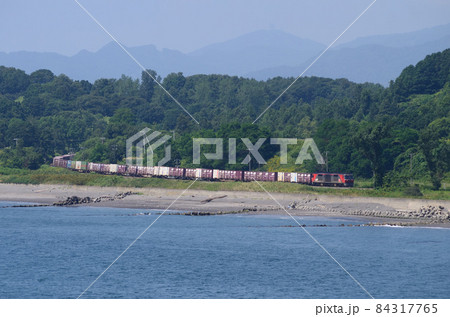 薄っすらと浮かぶ洞爺の山々をバックに有珠の海岸線に姿を現した貨物列車 薄っすらと浮かぶ洞爺の山々をバックに有珠の海岸線に姿を現した貨物列車 84317765