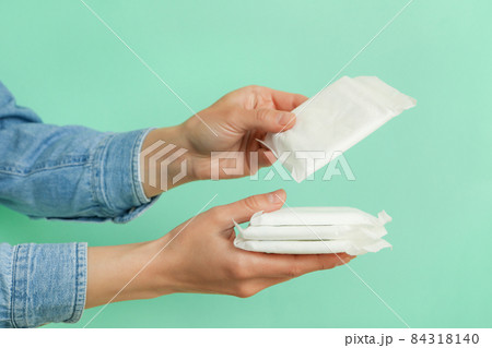 Female hands hold hygiene pads on mint background Female hands hold hygiene pads on mint background 84318140