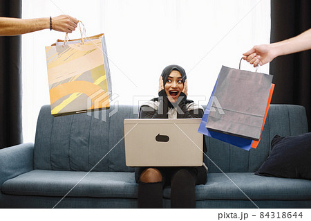 Arabic woman in headscarf using laptop at home, doing shopping online 84318644