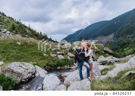 Romantic summer love story on a sunset in mountains. Young girl and boy in love. Romantic summer love story on a sunset in mountains. Young girl and boy in love. 84320237