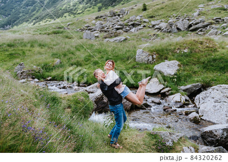 Romantic summer love story on a sunset in mountains. Young girl and boy in love. Romantic summer love story on a sunset in mountains. Young girl and boy in love. 84320262