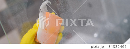 Cleaner in yellow rubber gloves washing glass in shower cabin closeup Cleaner in yellow rubber gloves washing glass in shower cabin closeup 84322465