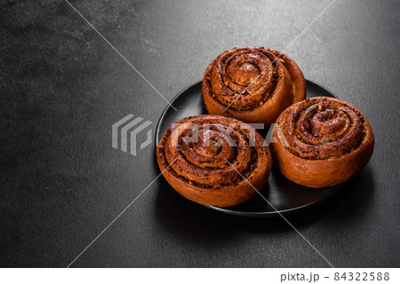 Freshly baked cinnamon roll with spices and cocoa filling on a black background Freshly baked cinnamon roll with spices and cocoa filling on a black background 84322588