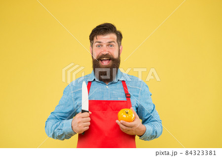 bearded man in red apron with yellow tomato. cooking  bearded man in red apron with yellow tomato. cooking  84323381