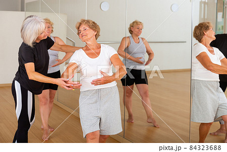 Aged women exercising ballet dance moves with trainer 84323688