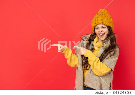 amazed child in knitted winter hat pointing finger on copy space, advertisement 84324358