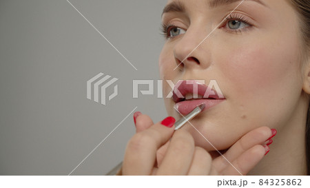 Makeup artist or stylist applies lipstick  to the lips of the female model. Visagiste making make up applying lipstick on a lip. Makeup artist or stylist applies lipstick  to the lips of the female model. Visagiste making make up applying lipstick on a lip. 84325862