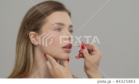 Makeup artist or stylist applies lipstick  to the lips of the female model. Visagiste making make up applying lipstick on a lip. Makeup artist or stylist applies lipstick  to the lips of the female model. Visagiste making make up applying lipstick on a lip. 84325863