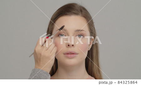 Applying mascara to the lashes. Make-up artist in beauty studio doing makeup for beautiful girl. Woman making up using comb for eyelashes. Young woman making makeup in dressing makeup room. Making Applying mascara to the lashes. Make-up artist in beauty studio doing makeup for beautiful girl. Woman making up using comb for eyelashes. Young woman making makeup in dressing makeup room. Making 84325864