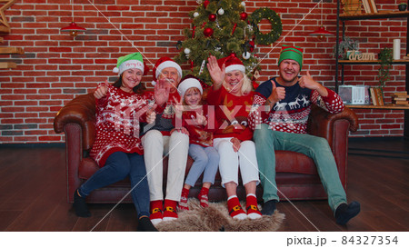 Laughing family waving hands hello, hi, greeting while taking selfie on smartphone at Christmas home Laughing family waving hands hello, hi, greeting while taking selfie on smartphone at Christmas home 84327354