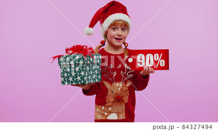 Girl kid in Christmas hat showing gift box and 90 Percent discount inscriptions banner text note Girl kid in Christmas hat showing gift box and 90 Percent discount inscriptions banner text note 84327494