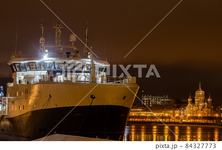 The panoramic footage of the winter night city Saint-Petersburg with picturesque reflection on water, big ship moored near Blagoveshchensky bridge, English embankment, cathedral on background 84327773